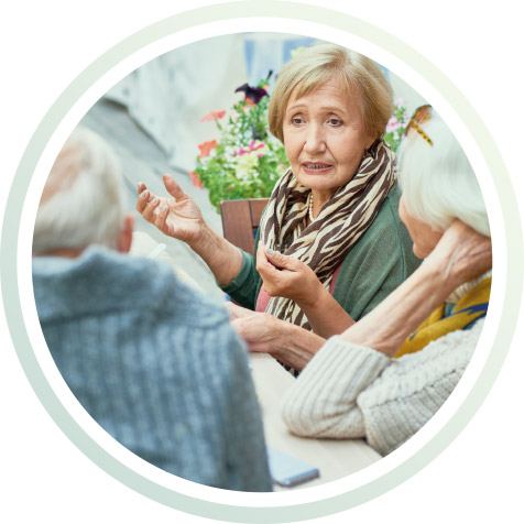 Ältere Menschen sitzen am Tisch und sprechn.