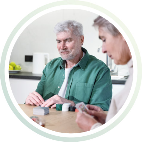 Mann und Frau sitzen am Tisch und spielen Karten.