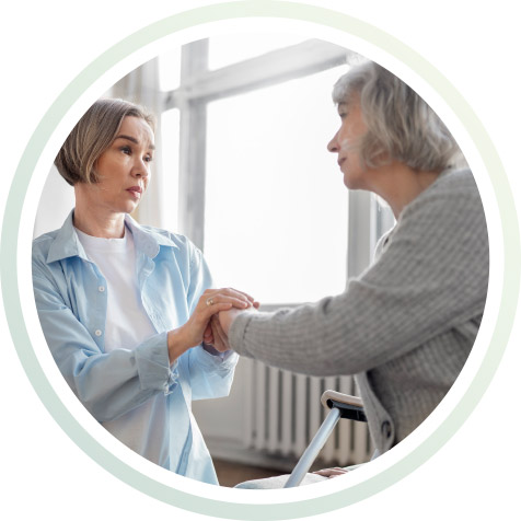 Eine junge Frau hält einer älteren Frau die Hand.