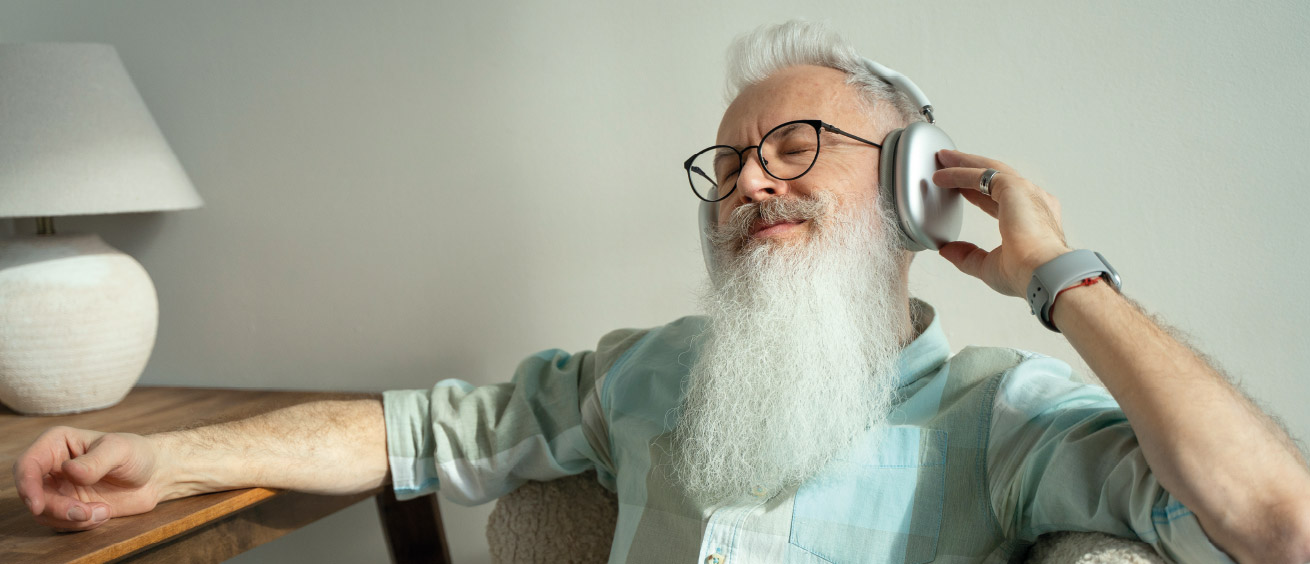 Ein Mann mit grauem Bart und Kopfhörern.