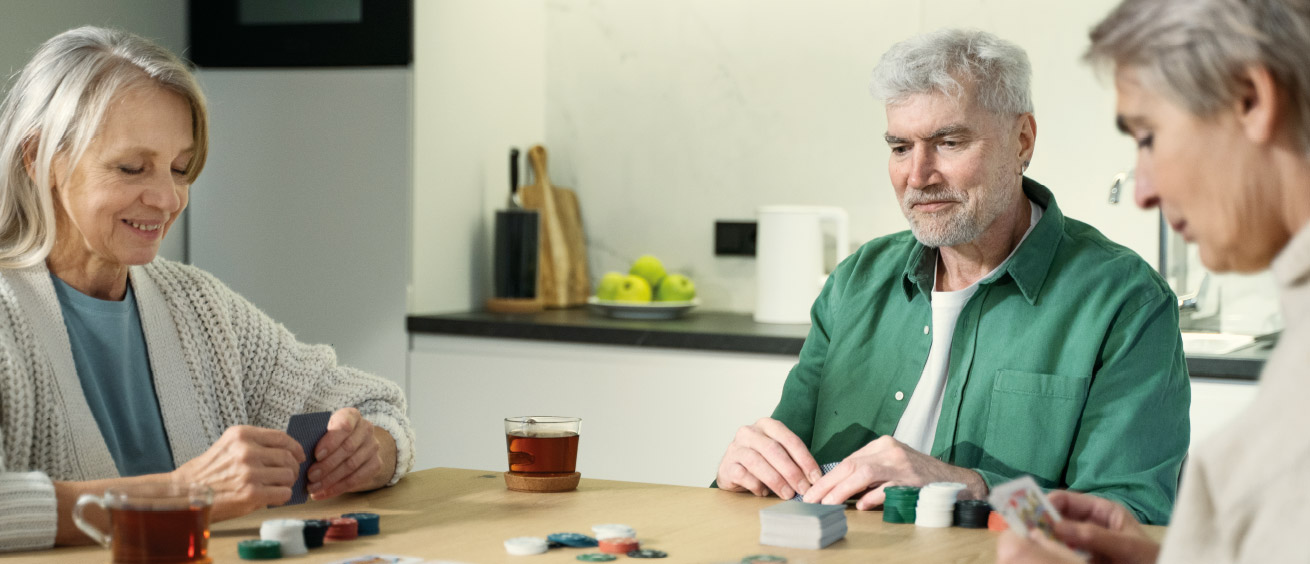 Eine Gruppe älterer Menschen sitzt am Tisch und spielt.